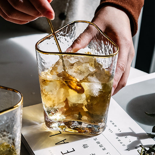 Glass cup with gold edge being filled with tea