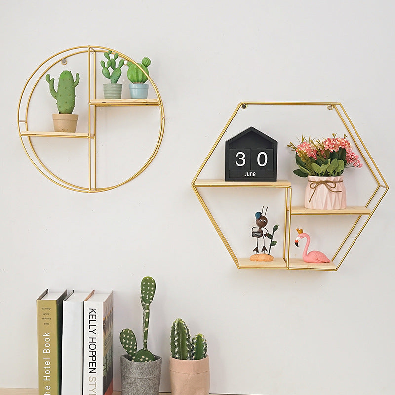 Geometric wrought iron wall shelf in gold finish on white wall
