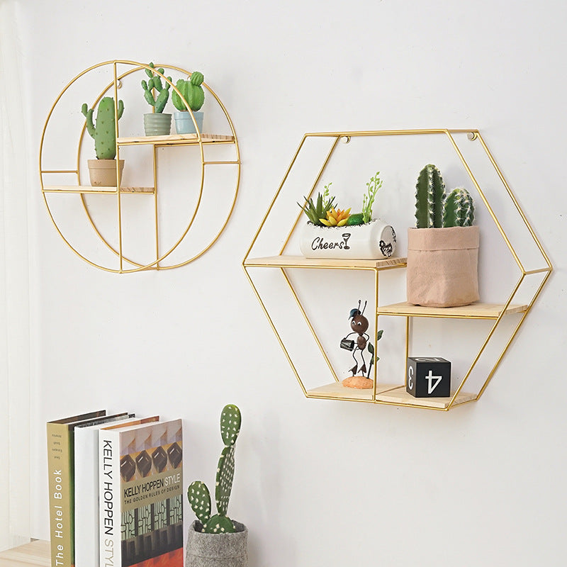 Geometric wrought iron wall shelf in gold finish on white wall

