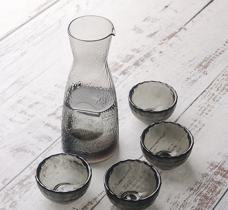 SHOND™ hammered glass sake set with pot and four cups on wooden table
