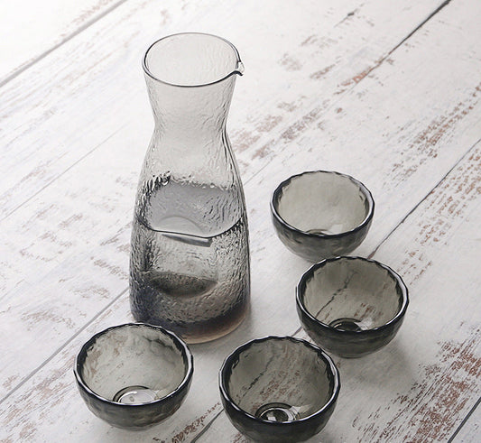 SHOND™ hammered glass sake set with pot and four cups on wooden table
