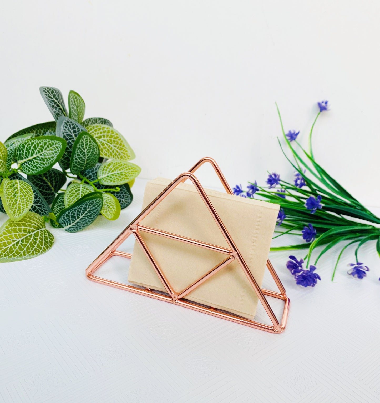 Rose gold triangle paper towel stand with packaging on shelf
