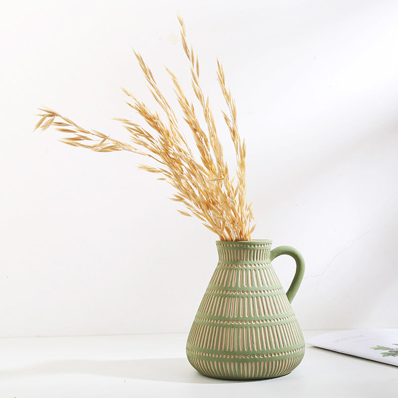 Small green ceramic vase with ear handles on wooden shelf
