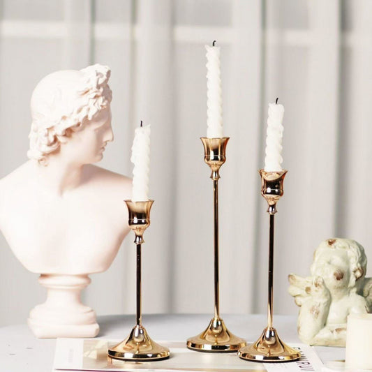 Set of 3 copper-tone candle holders on neutral table
