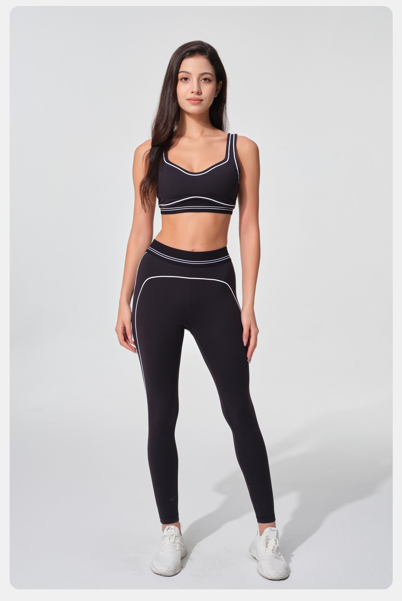 Woman wearing a black sports bra and leggings set on a white background