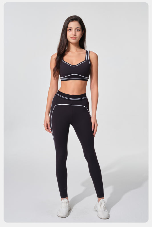 Woman wearing a black sports bra and leggings set on a white background