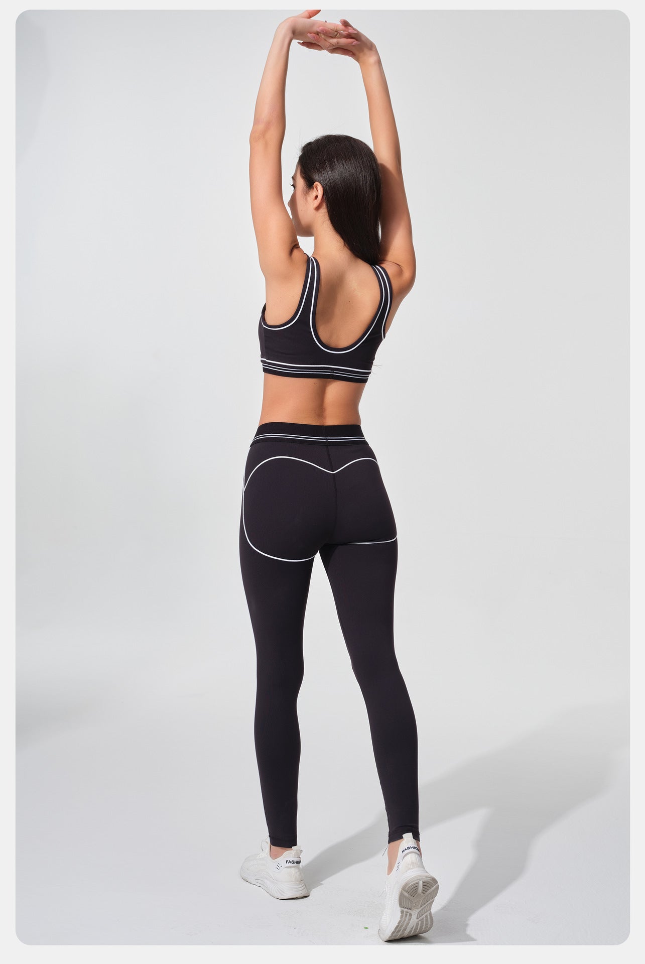 Woman in black athletic wear stretching on a white background
