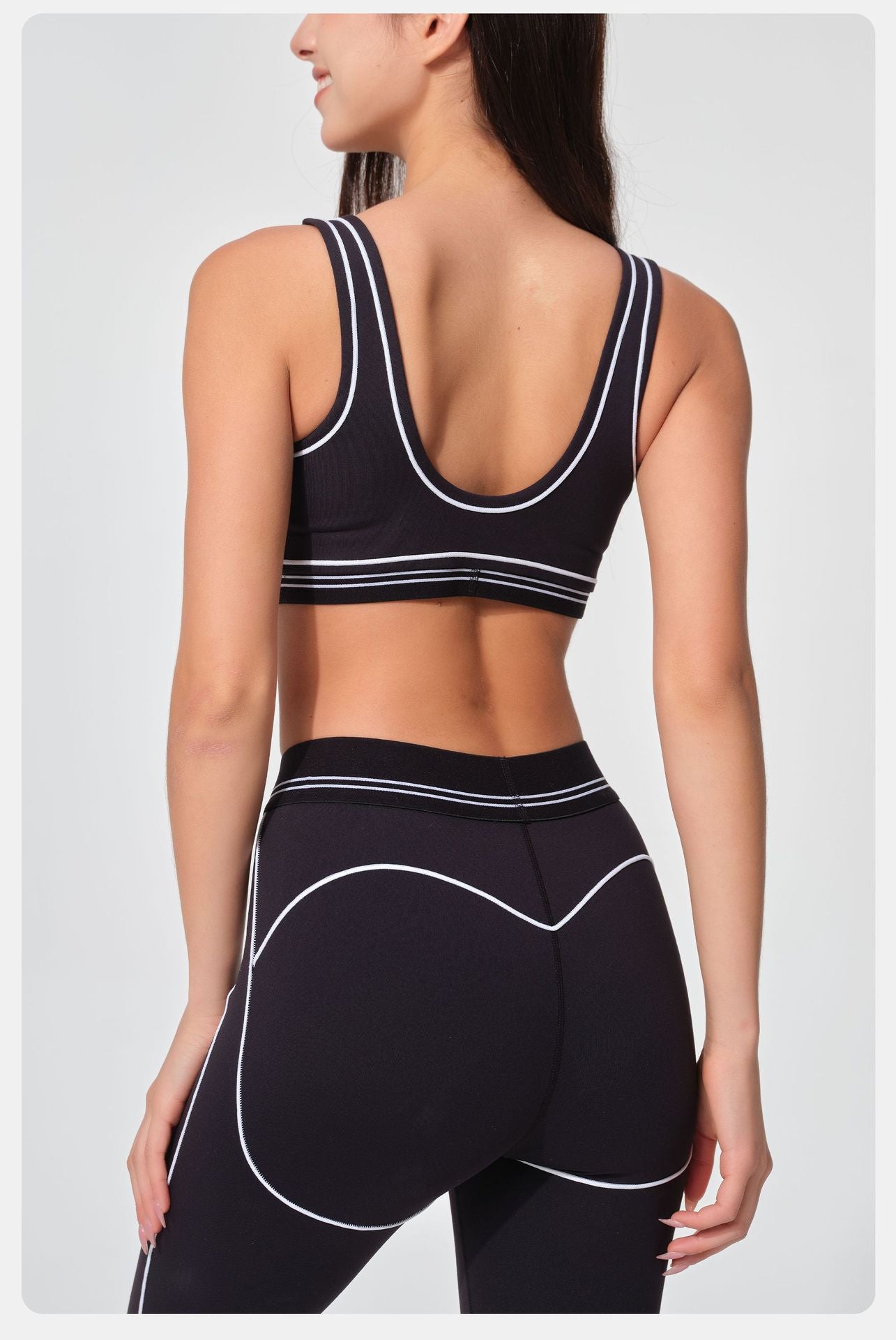 Black sports bra and leggings with white accents on a plain background