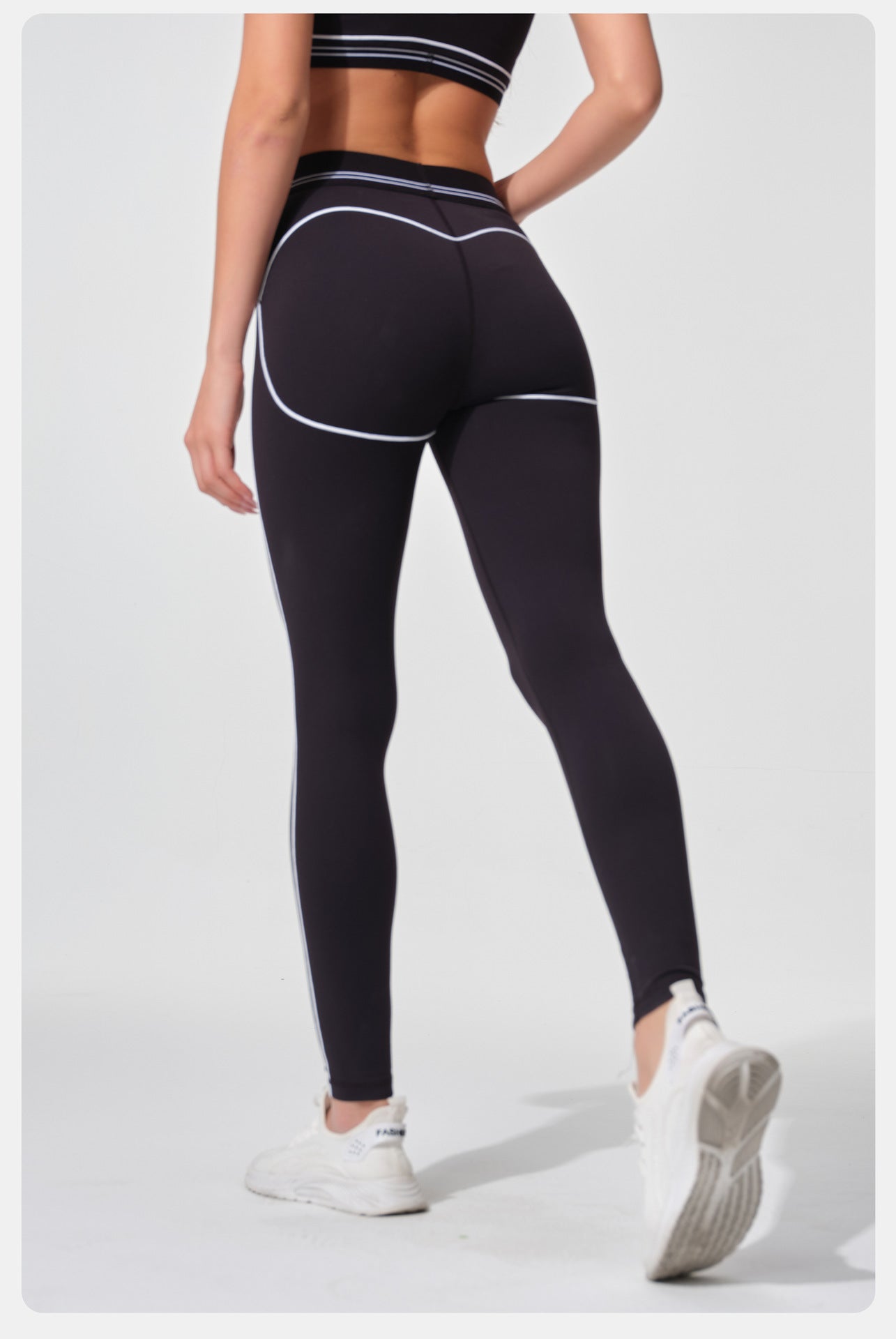 Person wearing black leggings with white accents on a light gray background