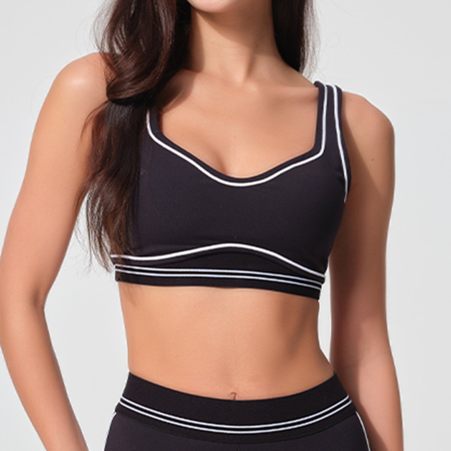 Black sports bra with white accents worn by a person on a plain background