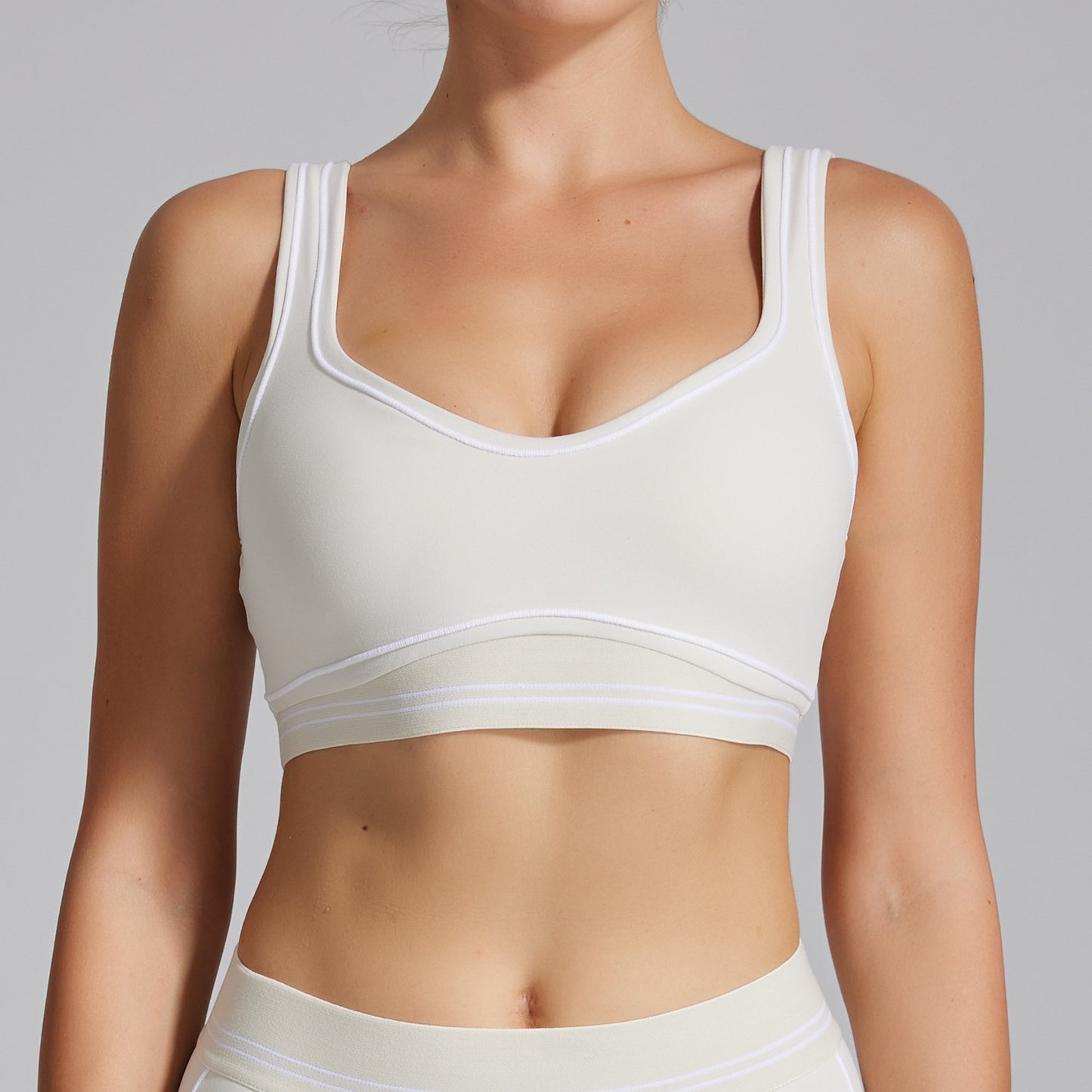 White sports bra worn by a person on a gray background