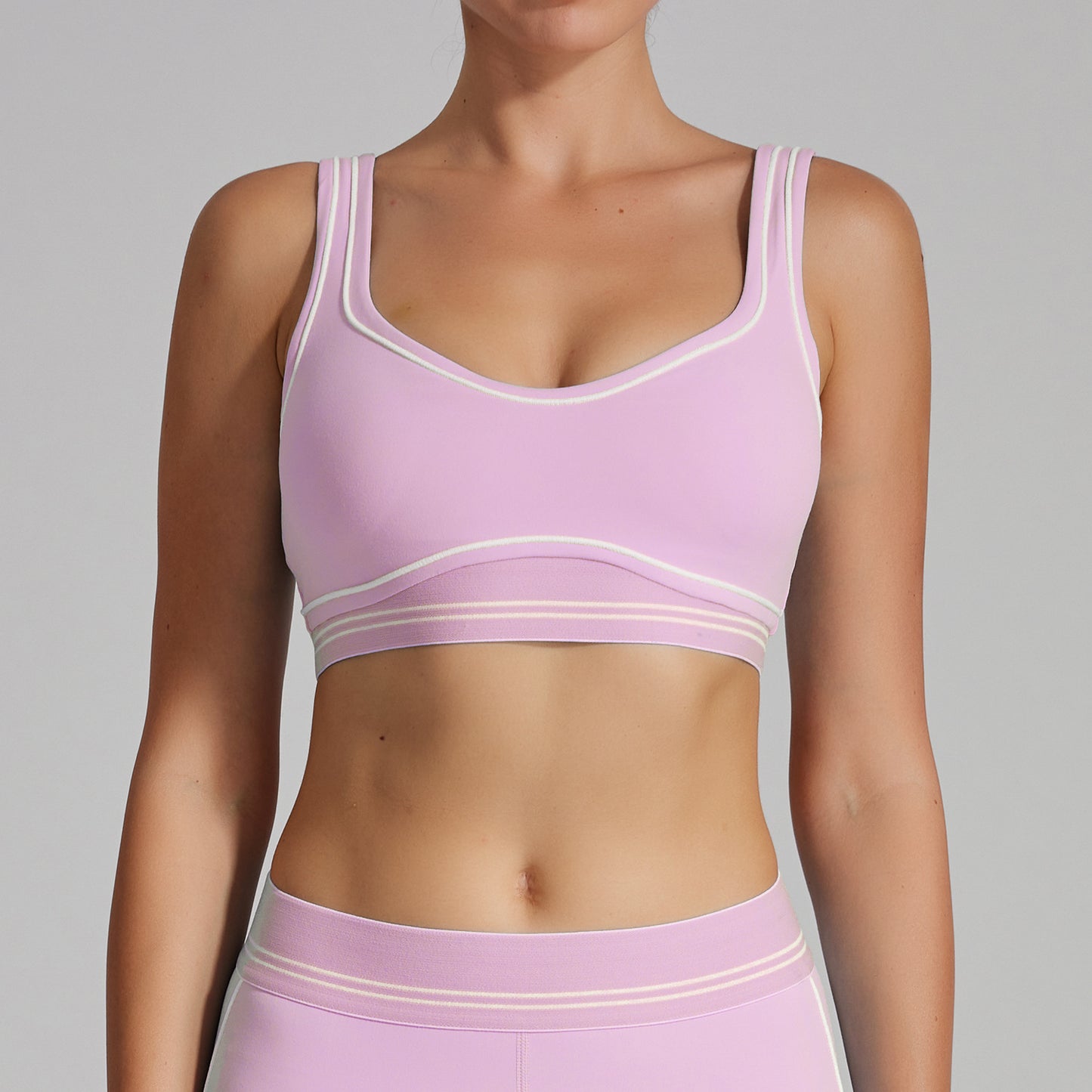 Person wearing a light purple sports bra and leggings set on a gray background