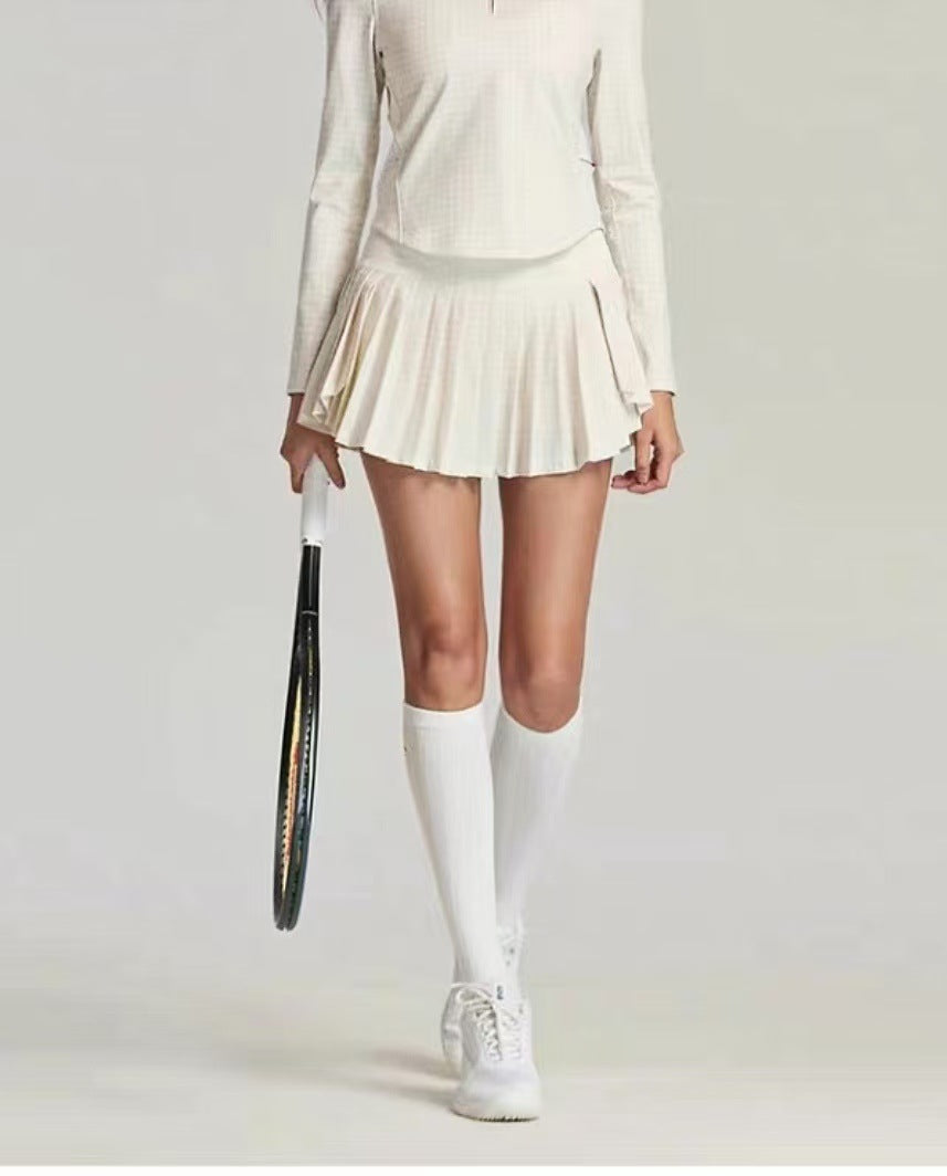 Person wearing a white tennis outfit with a skirt, top, and shoes, holding a tennis racket on a plain background.