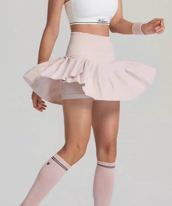 Person wearing a white top and pink tutu skirt with matching socks on a plain background