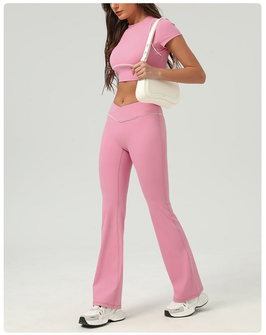 Woman wearing a pink athletic outfit with matching top and pants on a white background.