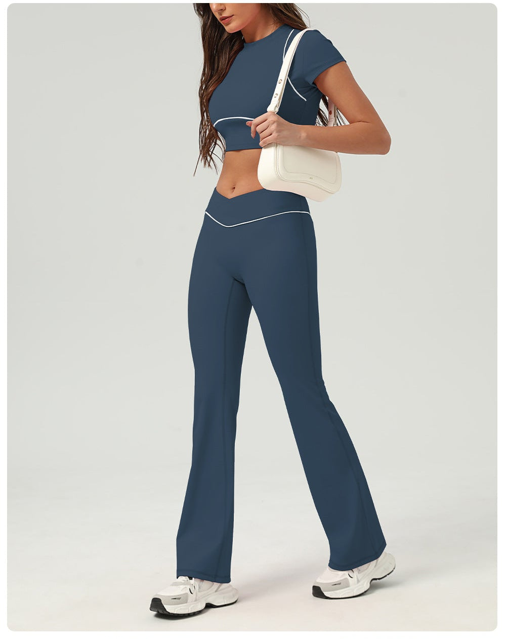 Woman wearing a blue athletic outfit with matching pants and top on a white background.