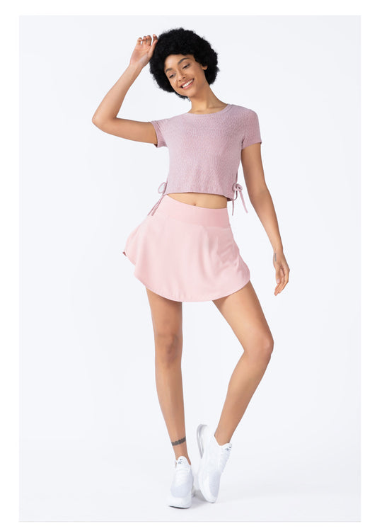 Woman wearing a pink outfit with a skirt and crop top on a white background