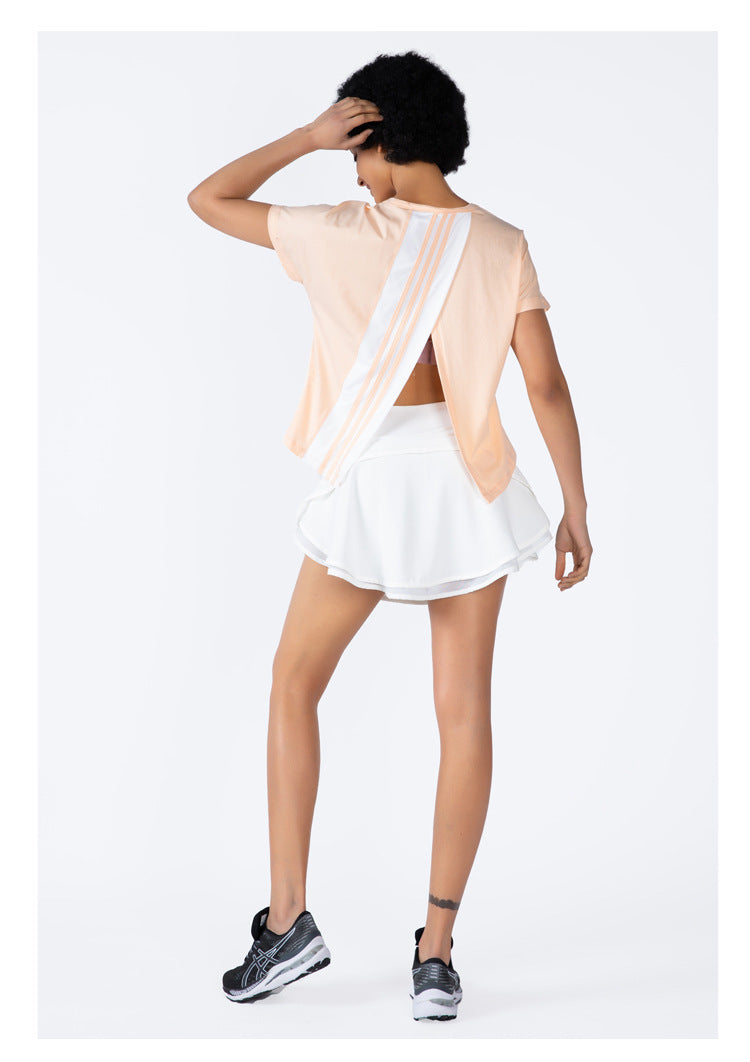 Person wearing a peach top with sheer panels and a white skirt on a white background