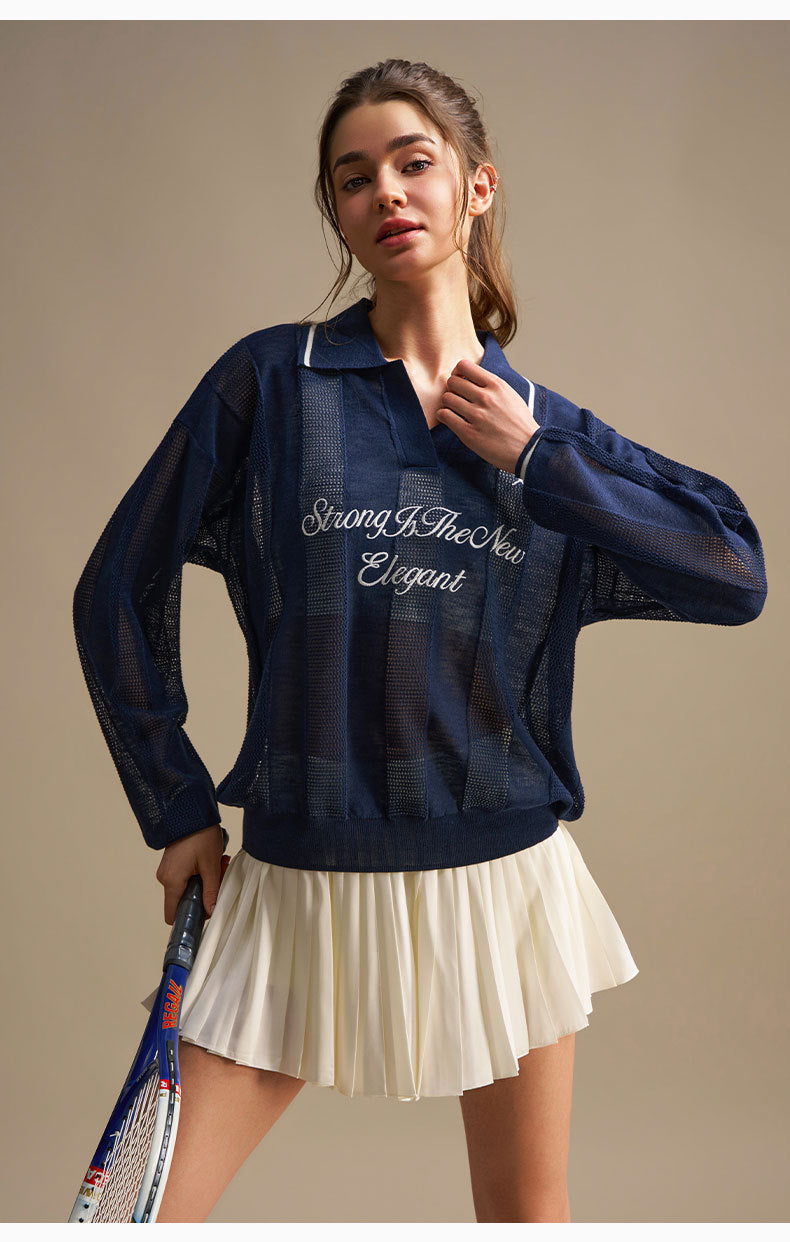 Woman wearing a navy blue jacket with text, holding a tennis racket on a beige background