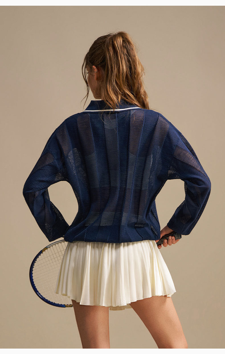 Person wearing a blue striped shirt and white pleated skirt holding a tennis racket on a beige background