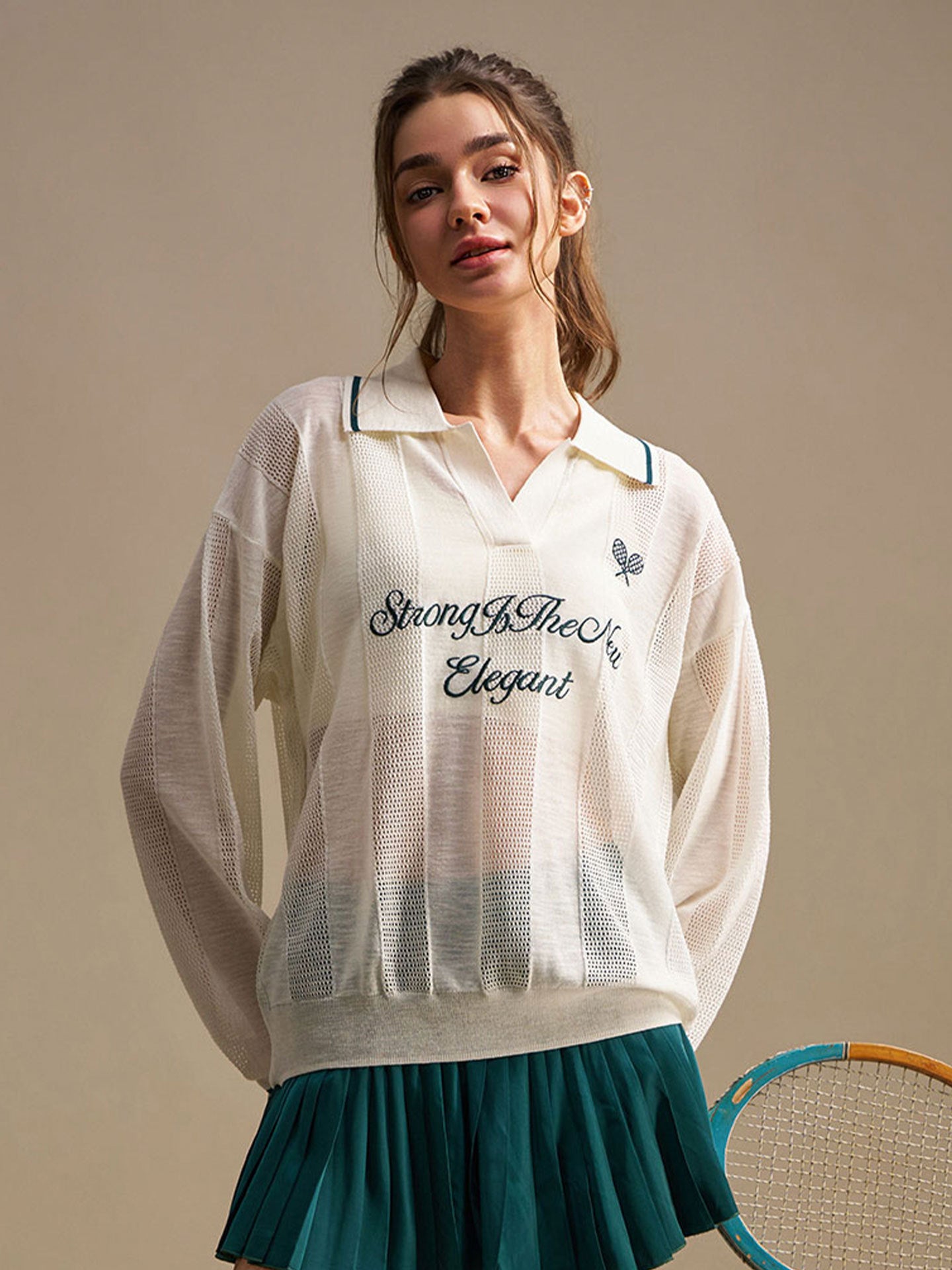 Woman wearing a white embroidered shirt with text, standing against a beige background