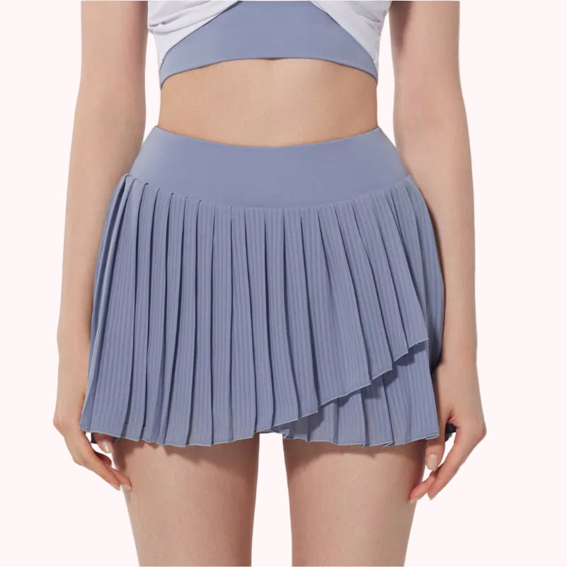 Person wearing a pleated blue skirt on a plain background