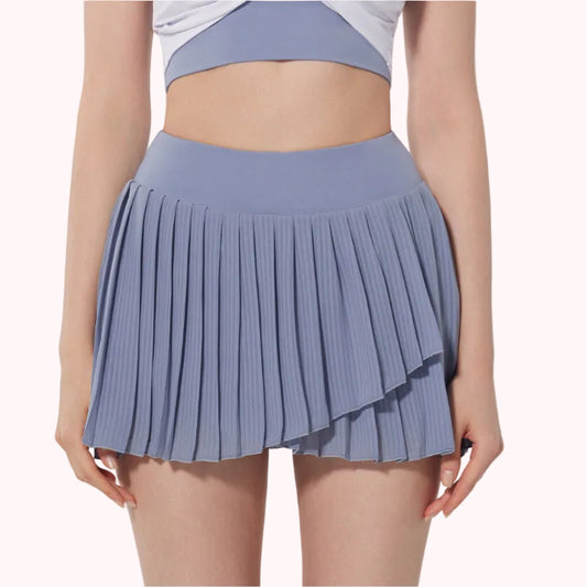 Person wearing a pleated blue skirt on a plain background