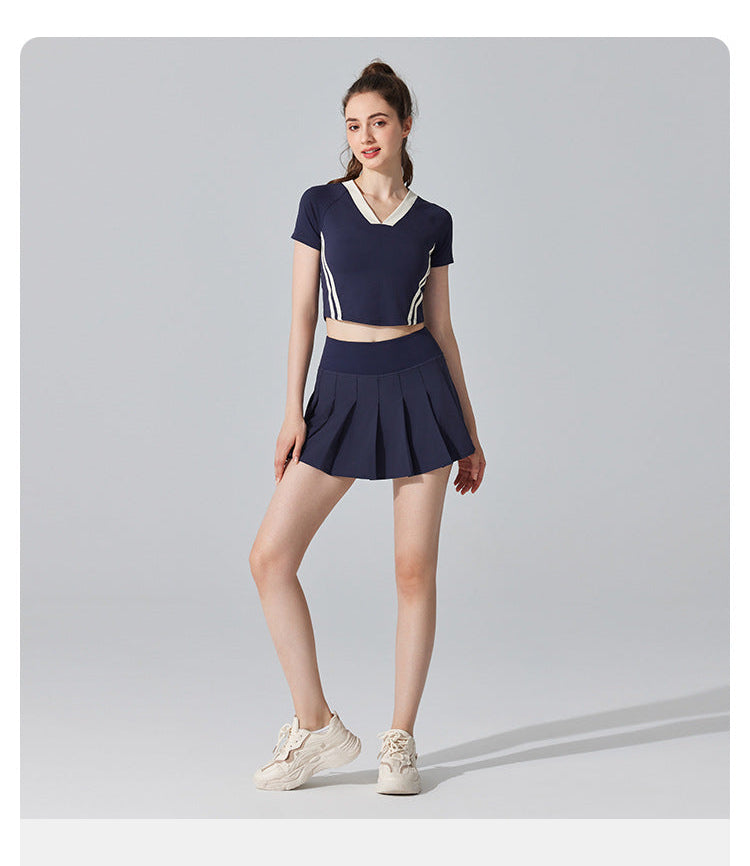 Woman wearing a navy blue athletic outfit with a skirt on a gray background