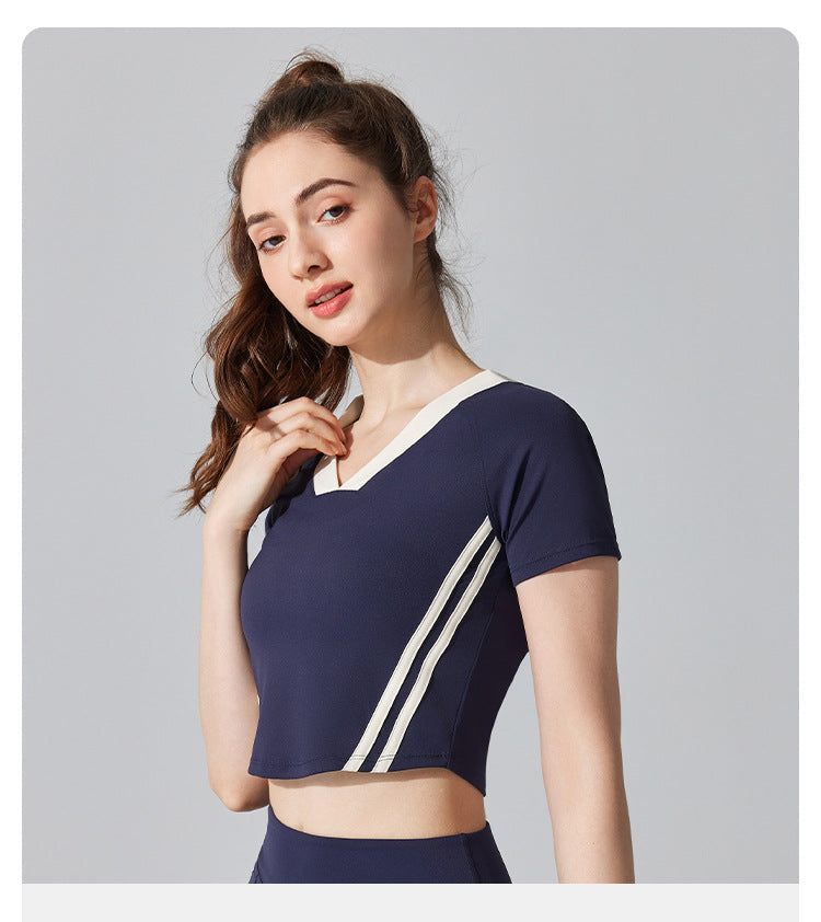 Woman wearing a navy blue athletic outfit with white stripes on a gray background