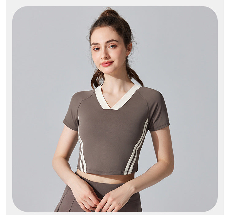 Woman wearing a brown athletic outfit with white accents on a gray background