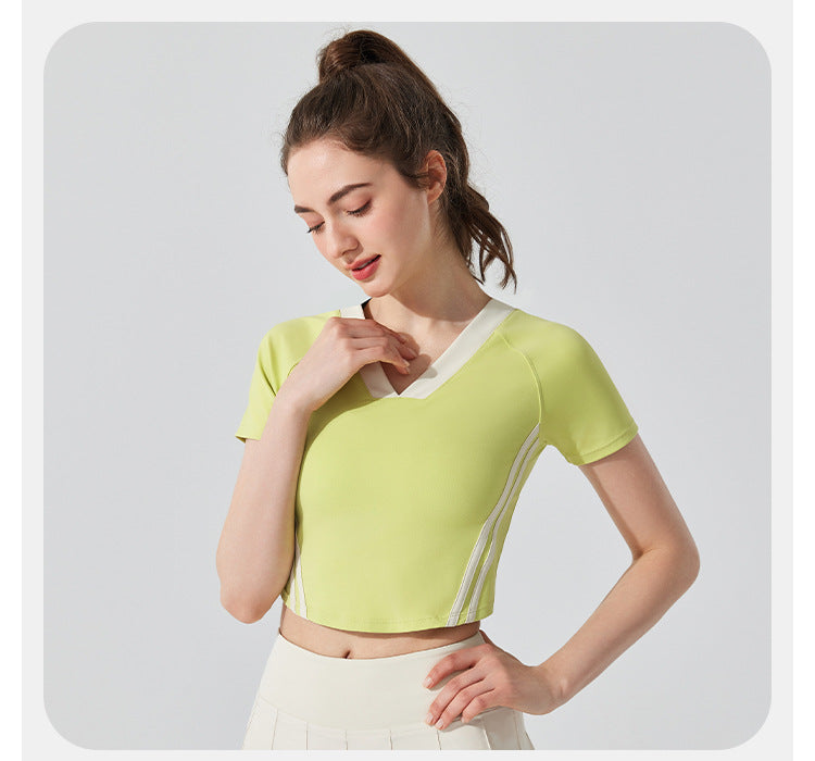 Woman wearing a light green crop top with white stripes on a plain background