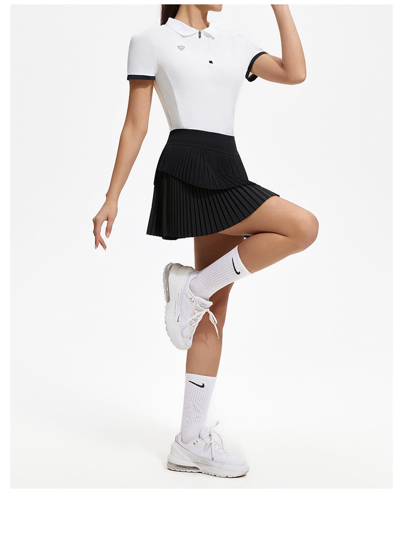 Person wearing a white polo shirt, black pleated skirt, and white sneakers on a white background