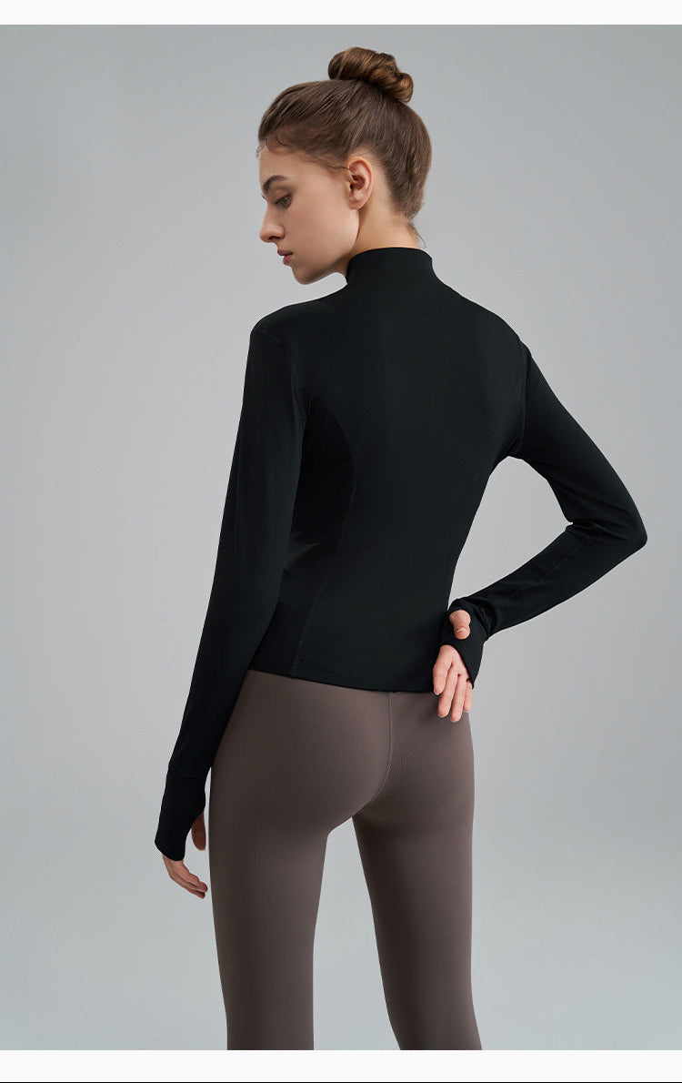 Woman wearing a black long-sleeve top and gray leggings on a gray background