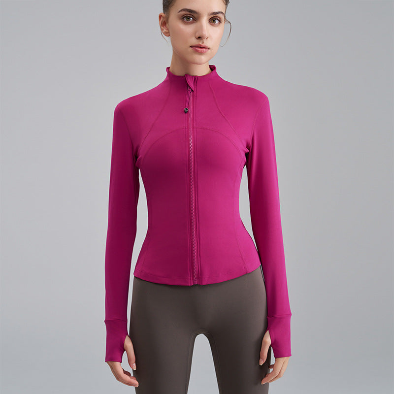 Woman wearing a pink athletic jacket and gray leggings on a gray background