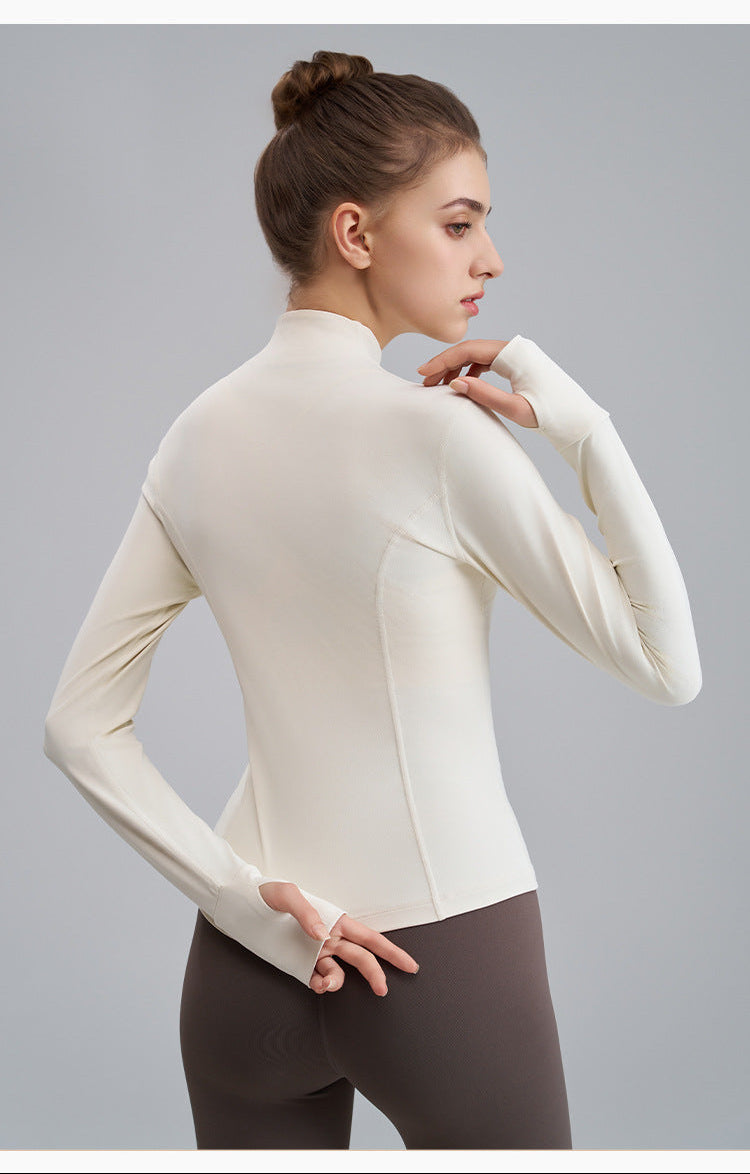 Woman wearing a white long-sleeve top and brown leggings on a gray background
